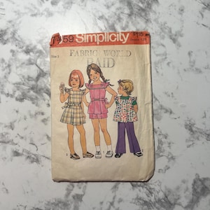 Puede incluir: Patrón de costura vintage Simplicity número 7459 para vestidos de niñas. El patrón es para las tallas 3-6 y presenta tres estilos de vestidos diferentes. El patrón está etiquetado como "Fabric World Paid" y tiene un precio de $ 1,15.