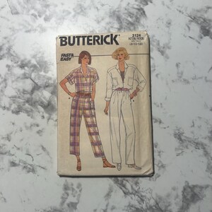 May include: Vintage Butterick sewing pattern 3124. The pattern features illustrations of a plaid jumpsuit and a white jumpsuit. The words "FAST & EASY" are printed on the front of the pattern.