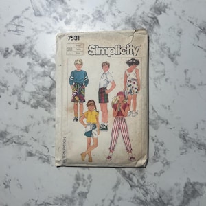 May include: Vintage Simplicity sewing pattern 7531 featuring illustrations of children's clothing. The pattern envelope shows various outfits, including shorts, tops, and striped pants. The Simplicity logo is prominently displayed.
