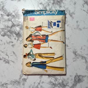 May include: A vintage Simplicity sewing pattern envelope for a women's skirt and pants pattern. The pattern is for sizes 14, bust 36, waist 27. The envelope features a colorful illustration of women wearing the different styles of skirts and pants.