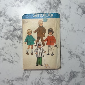 May include: Simplicity sewing pattern for children's clothing. The pattern is for sizes 3, 22, and 24. The pattern includes a blue coat, a red coat, and a white coat. The pattern also includes a blue balloon.