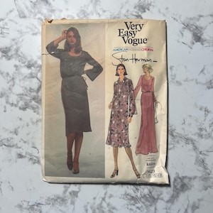 May include: Vintage Very Easy Vogue sewing pattern featuring designs by Stan Herman. The pattern envelope shows illustrations of dresses. The envelope is off-white with text and illustrations in black and pink.