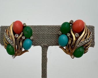 Könnte beinhalten: Vintage Clip-Ohrringe mit goldfarbenem Blattdesign. Jeder Ohrring hat korallenfarbene, grüne und türkisfarbene Cabochons und klare Strasssteine. Ein klassisches Schmuckstück.