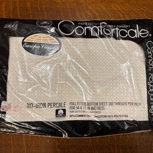 May include: A sealed package of a Comfortcale full fitted bottom sheet. The sheet is cream-colored with a subtle pattern and is designed for a 54 x 76 inch mattress. The package includes the text "Europa Classics" and "Cannon Royal Family."
