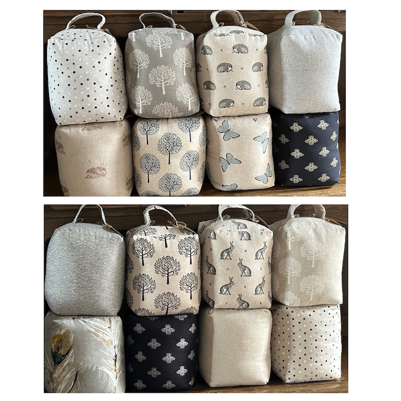May include: A set of 18 doorstops in various patterns and colors. The doorstops are made of fabric and have a variety of designs, including trees, butterflies, bees, and polka dots.