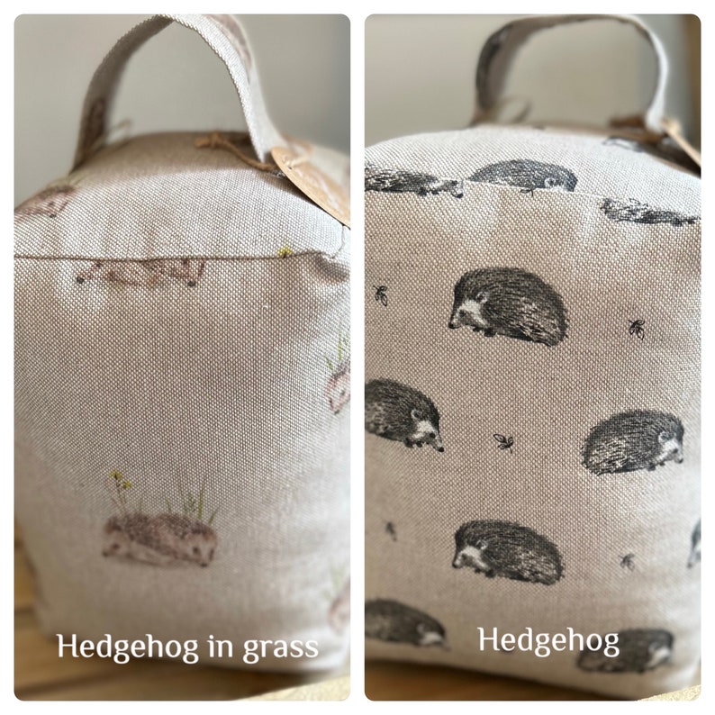 May include: Two beige doorstops with a hedgehog pattern. One doorstop has a pattern of hedgehogs in grass, the other has a pattern of hedgehogs only. Both doorstops have a brown handle.