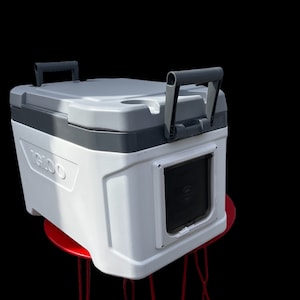 May include: White Igloo cooler with a black handle and a black door with a built-in bottle opener. The cooler is sitting on a red metal stool.