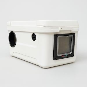 May include: A white plastic pet carrier with a rectangular shape. It features a circular opening, a slotted vent, and a small door with a black frame. The carrier has a hinged lid and is designed for pet transport.