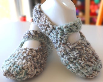 May include: A pair of crocheted slippers in a light blue and brown color scheme. The slippers have a strap across the top and are made with a chunky yarn.