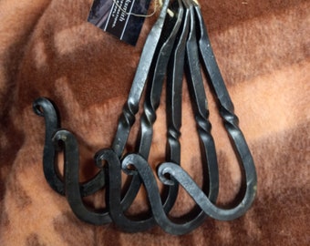 May include: Set of five black metal hooks with a twisted design. The hooks are handmade and have a rustic look. The hooks are tied together with twine and a tag that reads "Redfox Armory Blacksmith".