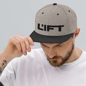 May include: A gray and black baseball cap with the word "LIFT" in black lettering on the front.