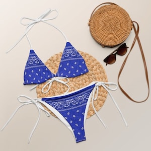 May include: Blue and white patterned bikini with a triangle top and a high-waisted bottom. The bikini is on a woven straw mat.