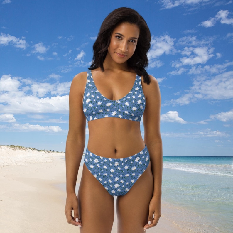 May include: A blue and white floral print bikini with a high-waisted bottom. The bikini top has a scoop neck and the bottom has a high-cut leg.