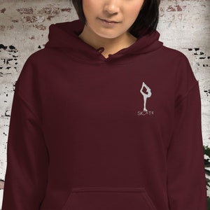 May include: Burgundy hoodie with a white silhouette of a figure ice skating and the word "SKATE" underneath.