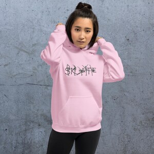 May include: A pink hoodie with a black graphic of ice skaters spelling out the word "SKATE".