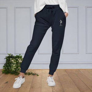 May include: Navy blue sweatpants with a white graphic of a person doing a yoga pose and the text "Na Mas Te".