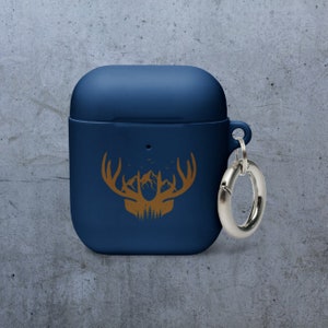 May include: A blue silicone case for wireless earbuds with a gold deer silhouette design and a silver metal carabiner.
