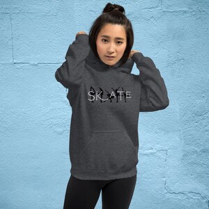 May include: A dark gray hoodie with a white graphic of the word "SKATE" with silhouettes of people ice skating.