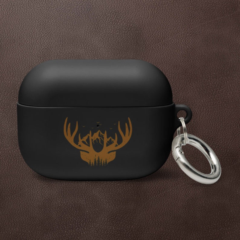 May include: Black silicone Airpods case with a gold deer silhouette design and a silver metal keychain.