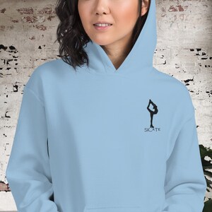 May include: A light blue hoodie with a black silhouette of a figure ice skating and the word "SKATE" underneath.
