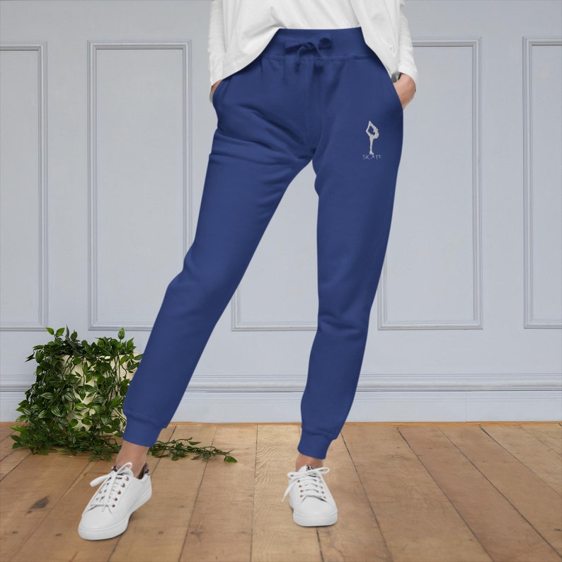 May include: Blue sweatpants with a white graphic of a figure skating pose and the text "Skate It" on the right leg.