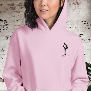 May include: Pink hoodie with a black silhouette of a figure ice skating and the word "SKATE" underneath.