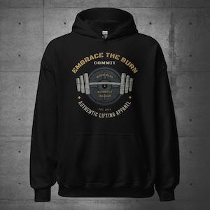 May include: Black hooded sweatshirt with a gold graphic of a weight plate and barbell. The graphic says "Embrace the Burn, Commit, Work Hard, Workout Harder, Authentic Lifting Apparel, Est. 2014".