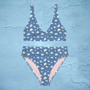 May include: A blue and white floral print bikini top and bottom. The top has a v-neck and the bottom is high-waisted.