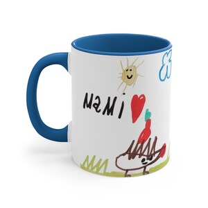 Puede incluir: Taza de cer&aacute;mica blanca con borde azul. La taza presenta un dibujo infantil de un sol, una nube, un coraz&oacute;n, un erizo y la palabra "MAMI".