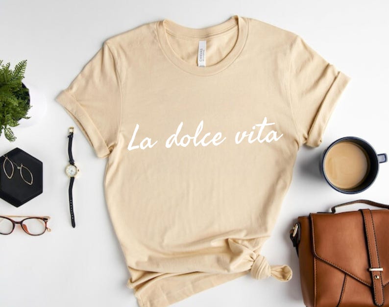 May include: A beige t-shirt with the text "La dolce vita" printed in white on the front.