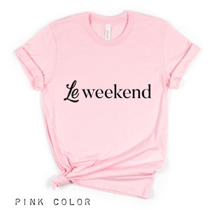 May include: A pink t-shirt with the text "Le weekend" in black lettering.