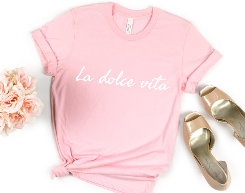 May include: A pink t-shirt with the text "La dolce vita" in white lettering.