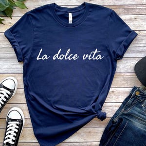 May include: A navy blue t-shirt with the text "La dolce vita" printed in white on the front.