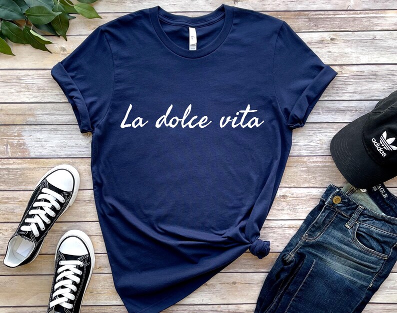 May include: A navy blue t-shirt with the text "La dolce vita" printed in white on the front.
