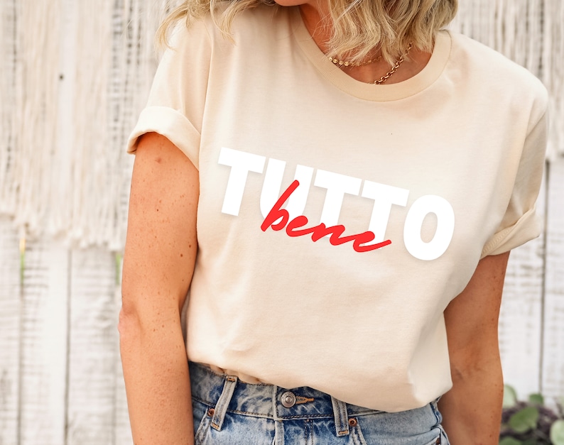 May include: A beige t-shirt with the words "TUTTO bene" printed in white and red.