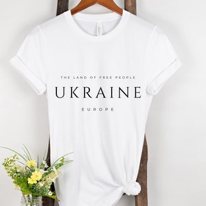 Pu&ograve; includere: Maglietta bianca con testo nero che recita "The land of free people, Ukraine, Europe".