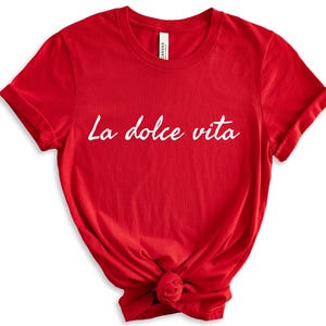 May include: Red short-sleeved t-shirt with the text "La dolce vita" in white.