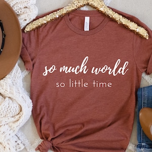 May include: A rust-colored t-shirt with the text "so much world so little time" in white lettering.