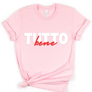 May include: Pink t-shirt with the text "TUTTO bene" in white and red lettering.