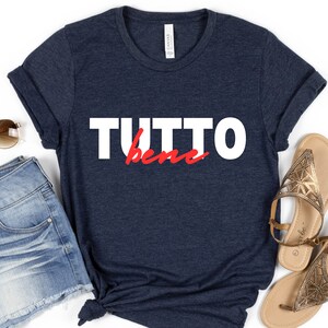May include: A navy blue t-shirt with the text "TUTTO bene" in white and red lettering.