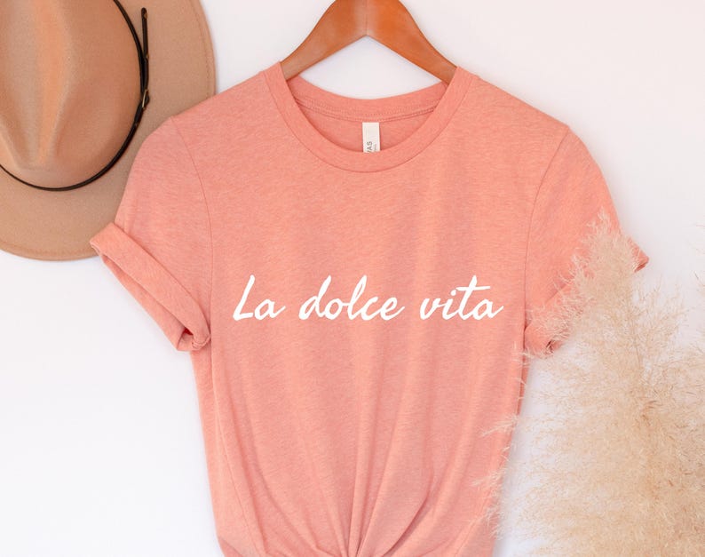 May include: A peach-coloured t-shirt with the text "La dolce vita" printed in white on the front.