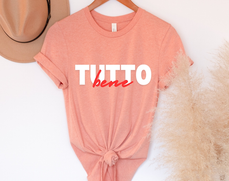 May include: A peach-colored t-shirt with the text "TUTTO bene" in white and red lettering.