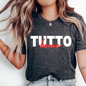 May include: A dark gray t-shirt with the text "TUTTO bene" in white and red lettering.