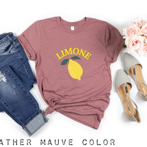 May include: A heather mauve t-shirt with the word "LIMONE" in yellow letters and a yellow lemon with green leaves.