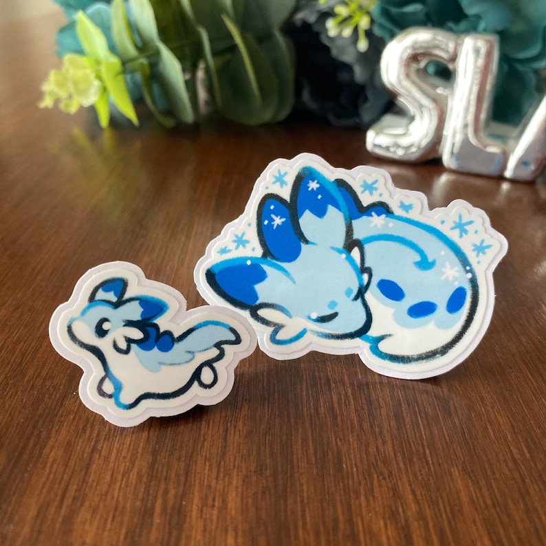 May include: Two blue and white cartoon stickers of a sleeping and a walking creature with snowflake designs.