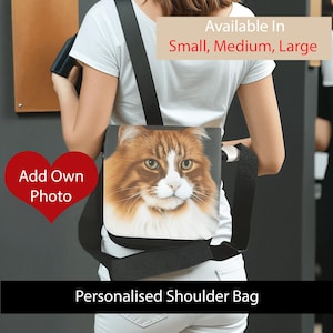 May include: A personalised shoulder bag with a fluffy ginger and white cat face. The bag has a black strap and is available in small, medium, and large sizes. The text "Add Own Photo" is displayed on a red heart. The words "Personalised Shoulder Bag" are displayed.