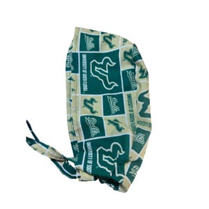 May include: A green and gold patterned scrub cap featuring the University of South Florida Bulls logo and text. The cap has a tie closure and is made of a lightweight fabric. The design includes the words "Bulls" and "University of South Florida".