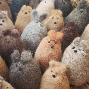May include: A collection of small, fuzzy, handmade animal toys in various shades of brown, gray, and white. The toys are made of wool felt and have different animal features, such as ears, eyes, and noses.