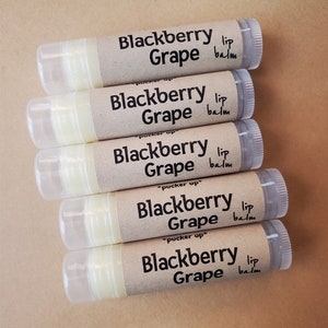 May include: Five tubes of Blackberry Grape lip balm stacked on top of each other. The tubes are clear with a brown label that says "Blackberry Grape lip balm" and "pucker up".