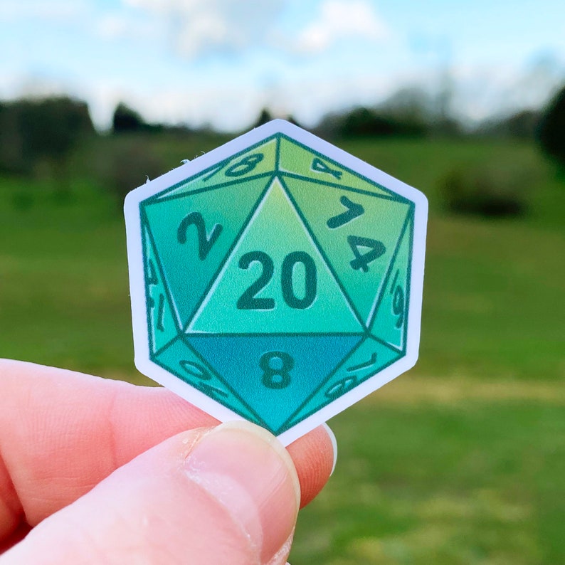May include: A green and blue 20-sided die sticker with white numbers. The sticker is shaped like a die and has a gradient colour scheme.